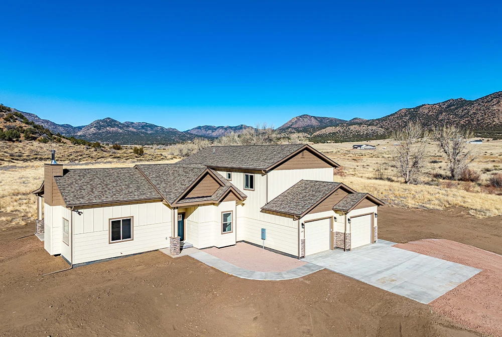 Custom-built Helton Construction home in Fremont County, Colorado featuring a light-colored exterior and attached garage with mountain views in the background